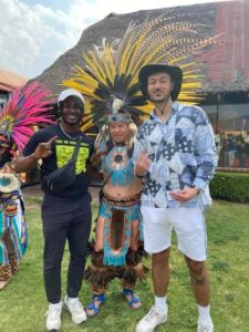 Two men standing next to a ritual dancer dressed in traditional Mexican style