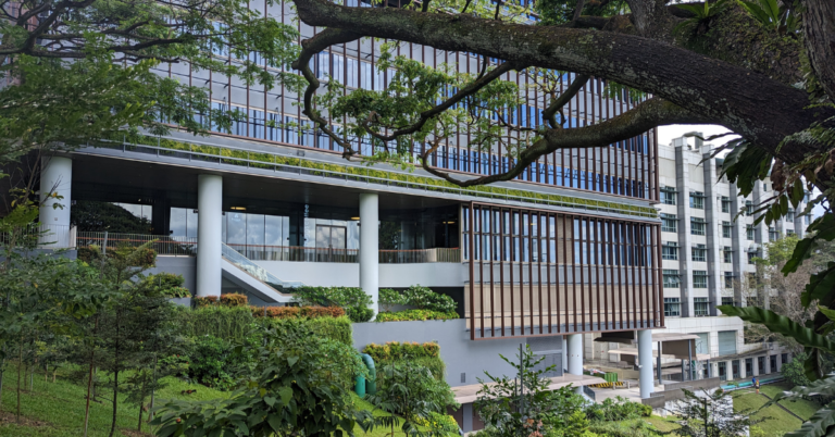 Image of the side of a building with many windows and a small garden
