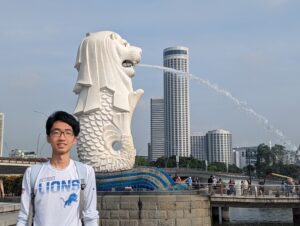 Student and the mythical statue Merlion which is a lion's head and the body of a fish.