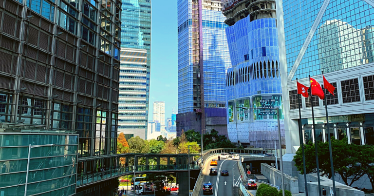 Tall glass buildings align a highway entrance ramp with few cars advancing in a central corridor of Hong Kong.