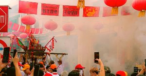 Smoke covers an outdoor market during a festival.
