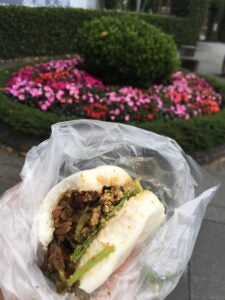 close up view of a pork belly sandwich wrapped in plastic