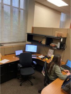 student at a desk working with fluorescent lights overhead