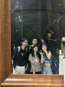 Four friends standing in front of a mirror taking a selfie.