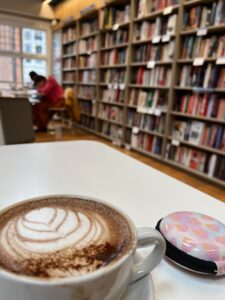 A cozy bookshop with shelves filled with numerous books and a cup of coffee on top of a white table.