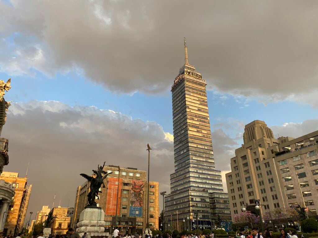Grey clouds behind a large tower building with lots of windows and a horse statue.