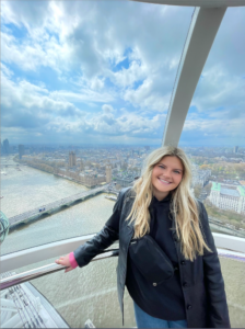 Girl in black jacket smiling while on the London eye overlooking the city of London