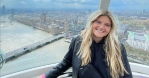 Girl in black jacket smiling while on the London eye overlooking the city of London