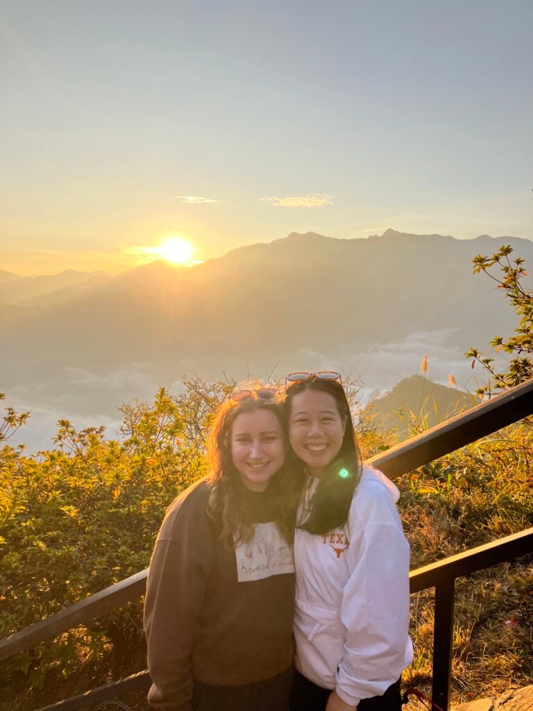 Photo of two female students smiling in long sleeve shirts