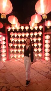Student smiling in front of red and white lanterns at night