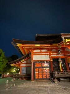 A magnificent Japanese shrine is orange and yellow with a brown roof.