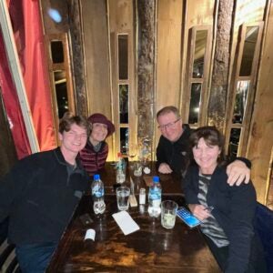 Three adults and one young man sit at a table full of soft drinks smiling at the camera.