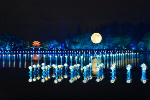 Blue floating lights on top of a river during a full moon.
