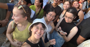 Students wait in a crowded plaza and take a selfie to pass the time.
