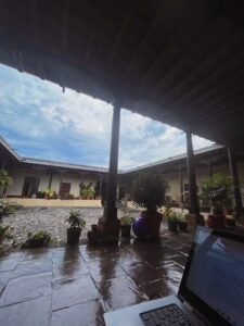 The inside of a residential home has a titled porch that is covered by a roof and welcomes visitors before entering the door of a cream colored, one-story house.