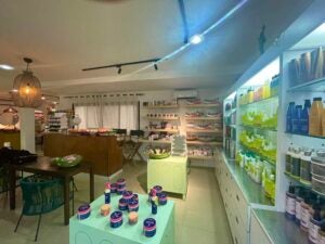 The interior of a beauty supply store shows recess lighting illuminating products on a shelf and on display next to a couch.