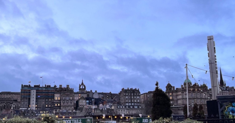 Wide view of an old building that looks like a castle on top of a small hill. A dark sky is overhead.