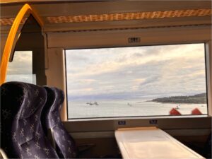 The inside of a train view while the train is en-route and crossing over a body of water.