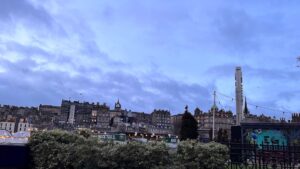 Wide view of an old building that looks like a castle on top of a small hill. A dark sky is overhead.