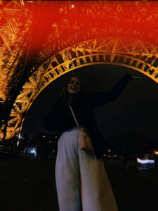 Girl standing against the illuminated Eiffel Tower at night, with a captivating red photo edit that contrast between darkness and stark red