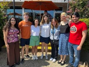 Seven joyful friends in casual attire, enjoying a sunny day, captured with bright smiles.