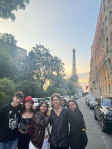 Five students posing on a street in front of the Eiffel Tower during the sunrise in Paris