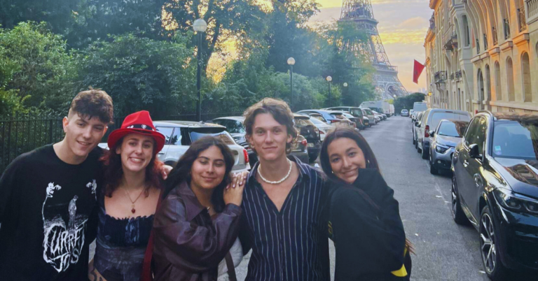 Students posing in front of the Eiffel Tower during the sunrise in Paris.