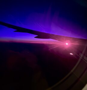 View from the plane of the sunrise. There are hues of deep blue, purple and pink.