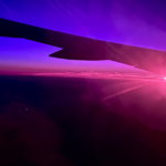 View from the plane of the sunrise. There are hues of deep blue, purple and pink.