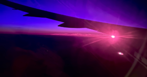 View from the plane of the sunrise. There are hues of deep blue, purple and pink.
