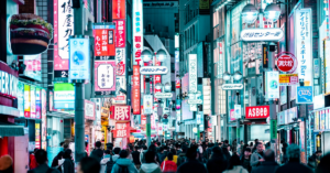 A busy street in Tokyo is filled with loud digital advertising and tall buildings