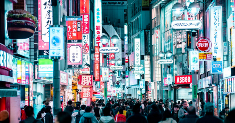 A busy street in Tokyo is filled with loud digital advertising and tall buildings