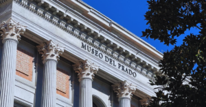 A stunning image of the museo del prado building facade on a bright, sunny day. The building displays several large columns and ancient architecture.