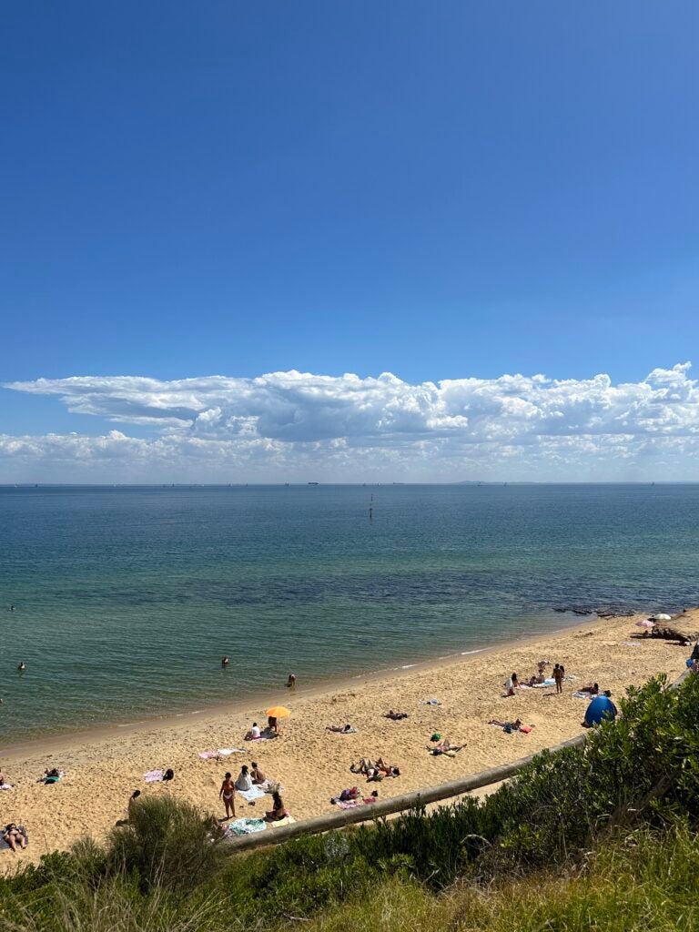 A sandy beach where people are sitting enjoying the sun and company