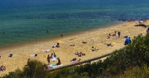 A sandy beach where people are sitting enjoying the sun and company