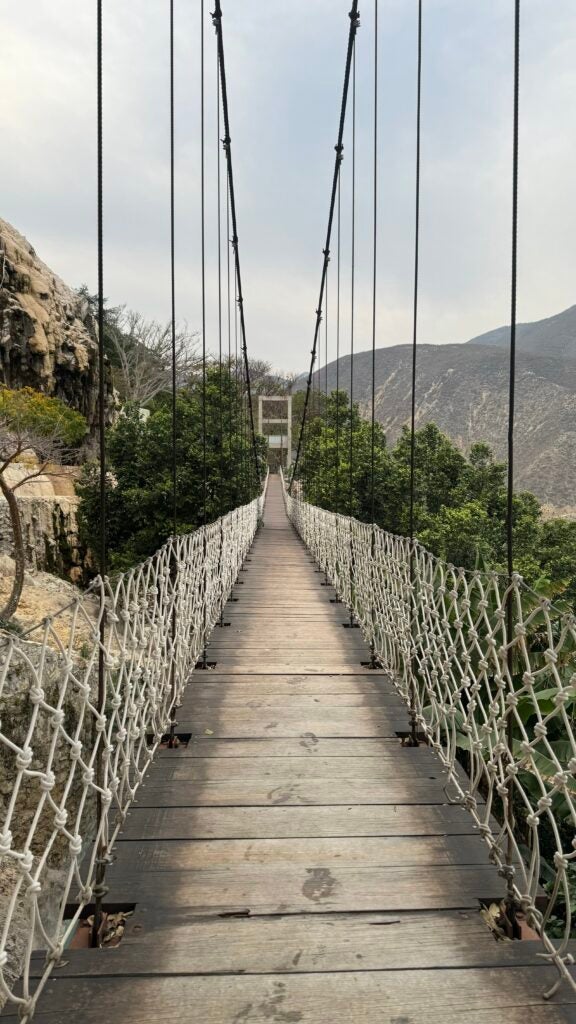 An older wooden bridge with ropes on either side and side netting
