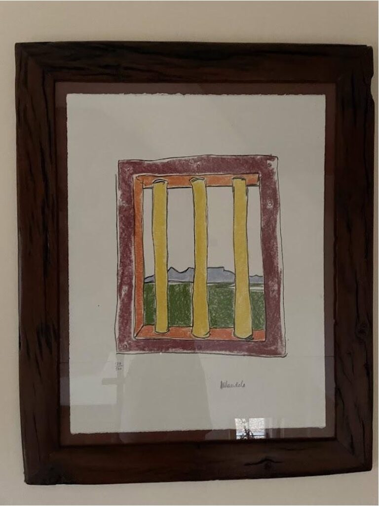 A simple drawing on white paper of three yellow columns surrounded by orange and red frame and hills of green in the back