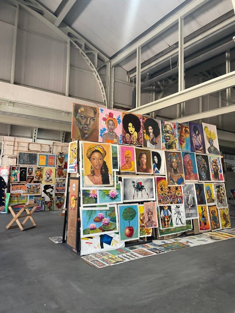 Several art photos of canvas paintings in a building.