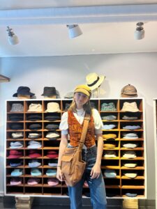 A student at a hat shop smiles happily.