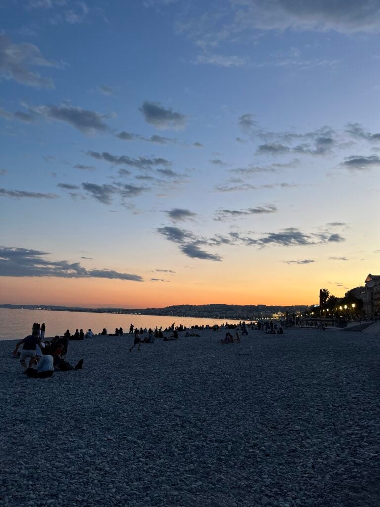 The sunset is orange, yellow, and parts of red on a beach.