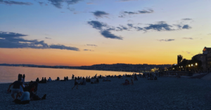 The sunset is orange, yellow, and parts of red on a beach.
