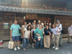 Group of students stand outside of a traditional japanese house