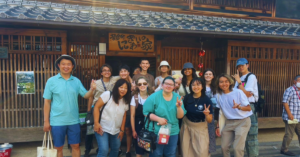 Group of students stand outside of a traditional japanese house