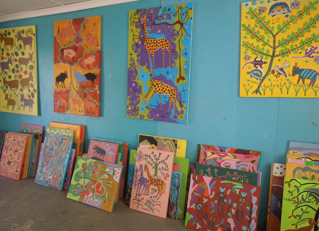Several painted images are on display on a teal wall