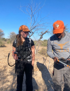 A student and a professor wearing UT burnt orange hats prepare fieldwork outside