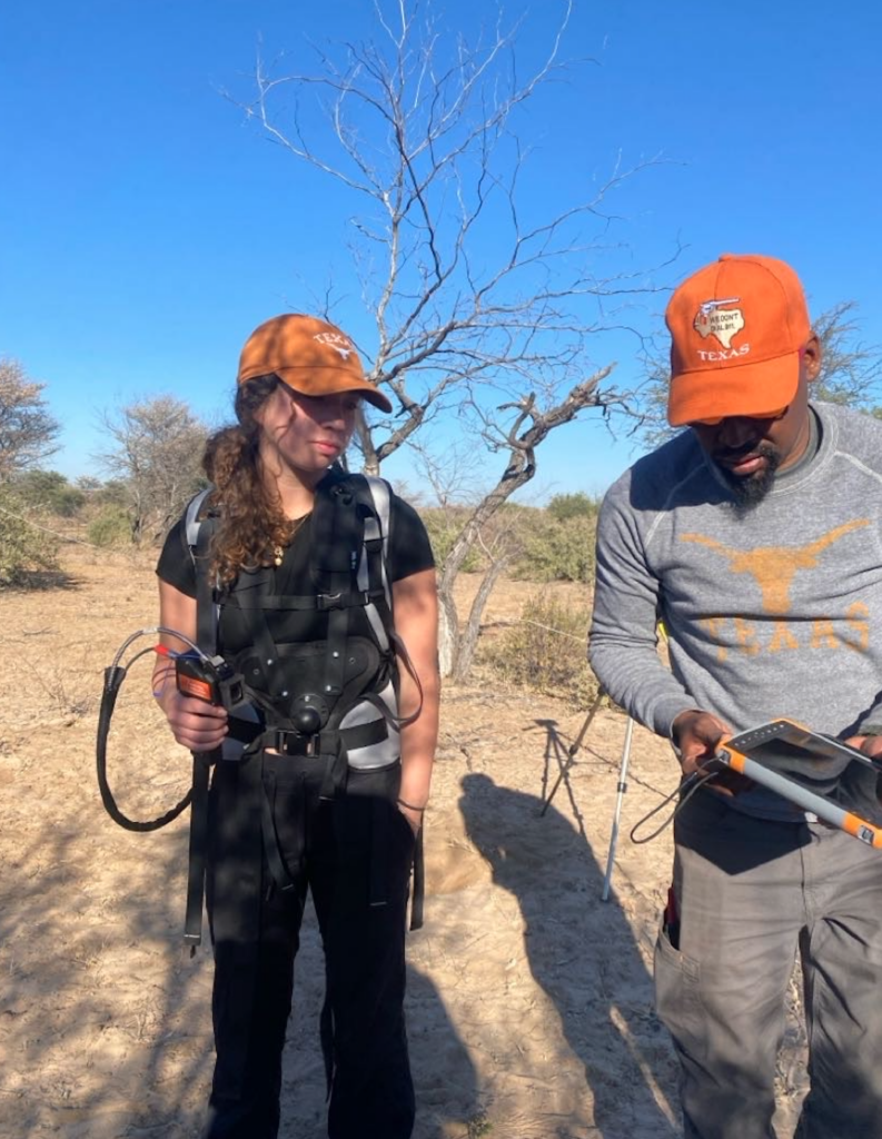 A student and a professor wearing UT burnt orange hats prepare fieldwork outside