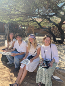 Four students smile at the camera while waiting outdoors