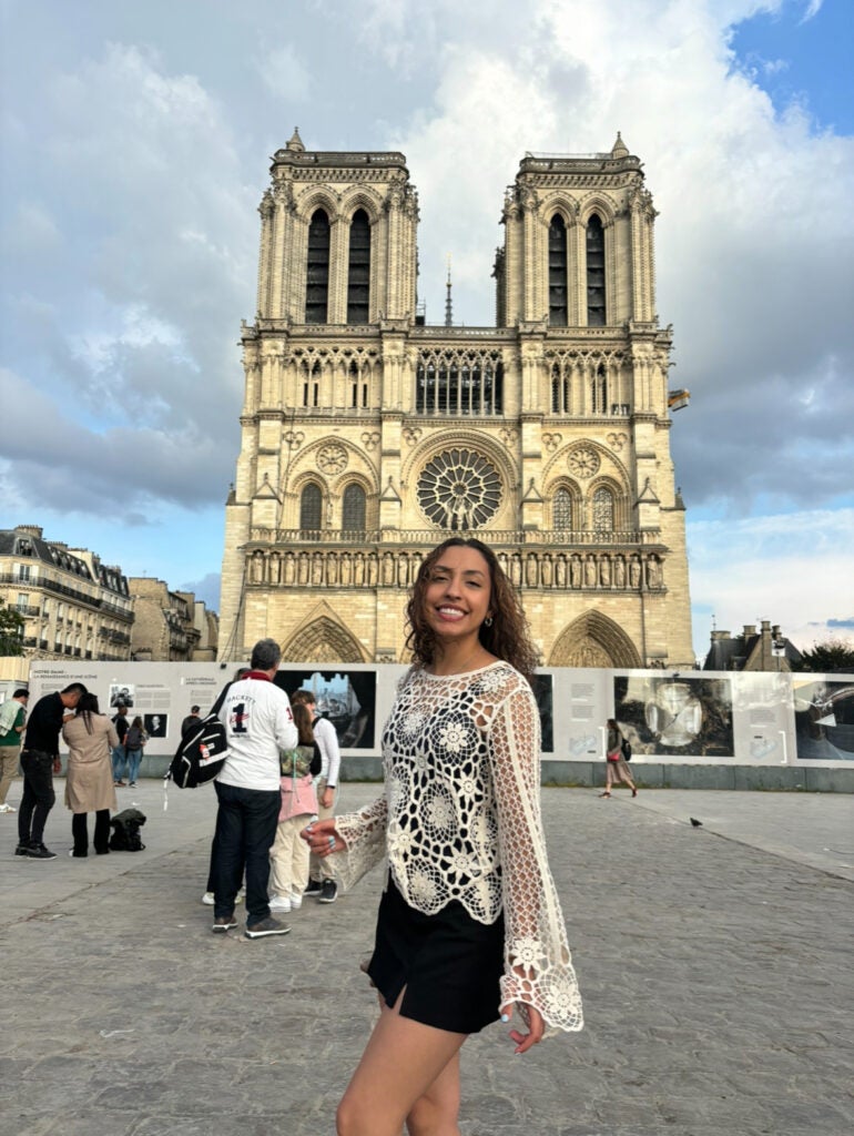 Girl poses in front of the Notre-Dame cathedral while tourists mosey around