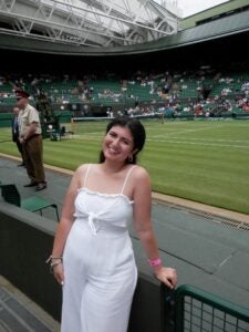 Student in all white smiles at the camera while at Wimbledon.