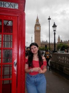 Student smiles as they stand in front of Big Bend and the famous red telephone booth.